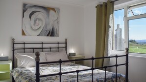 A bedroom with a bed, a nightstand, a lamp, a painting, a window with curtains, and a view of a landscape. - 2 bedroom accommodation in Crieff (Crieff)