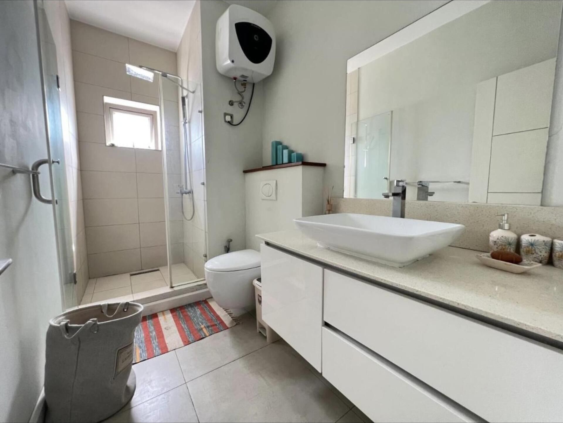 A modern bathroom with a walk-in shower, a toilet, a large sink, and a mirror.
