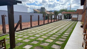 Um pátio pavimentado com um desenho padronizado, um banco de madeira e um edifício ao fundo.