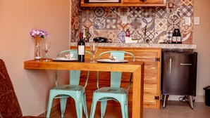 Uma cozinha com mesa de madeira, duas cadeiras azul-turquesa, micro-ondas e geladeira.