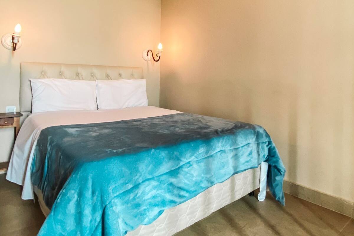 A single bed with a headboard, two bedside tables, and two wall-mounted lamps.