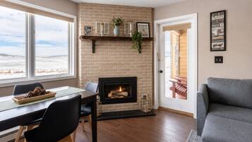 Una sala de estar con chimenea, un comedor con mesa y sillas, y un sofá.
