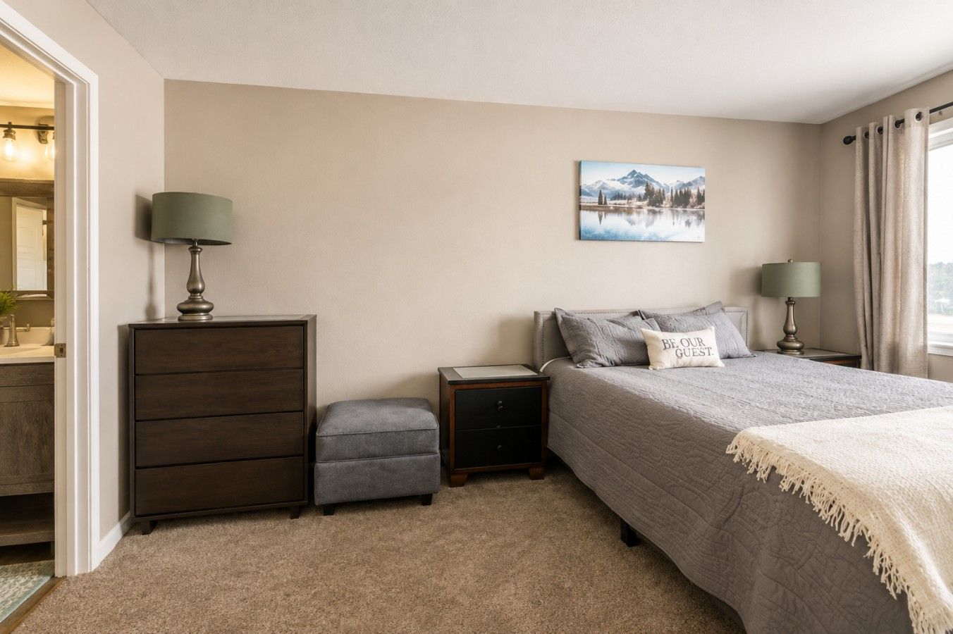 A bedroom with a bed, bedside tables, a dresser, a mirror, and a painting on the wall.