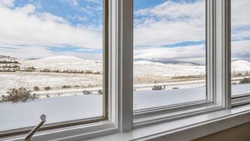 Una ventana con vistas a un paisaje nevado, que incluye casas y colinas distantes.