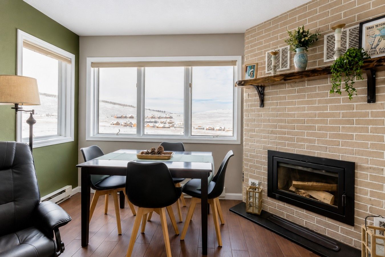 Un comedor con mesa y sillas, una chimenea y vistas a un paisaje nevado a través de amplios ventanales.