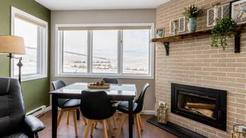Un comedor con mesa y sillas, una chimenea y vistas a un paisaje nevado a través de amplios ventanales.