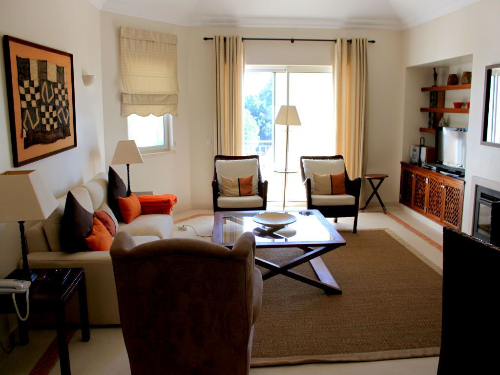 Un salon comprenant un canapé, deux fauteuils, une table basse et un téléviseur.