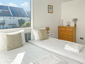 A bedroom with a bed, bedside tables, a dresser, a window with a view of buildings, and a framed picture on the wall.