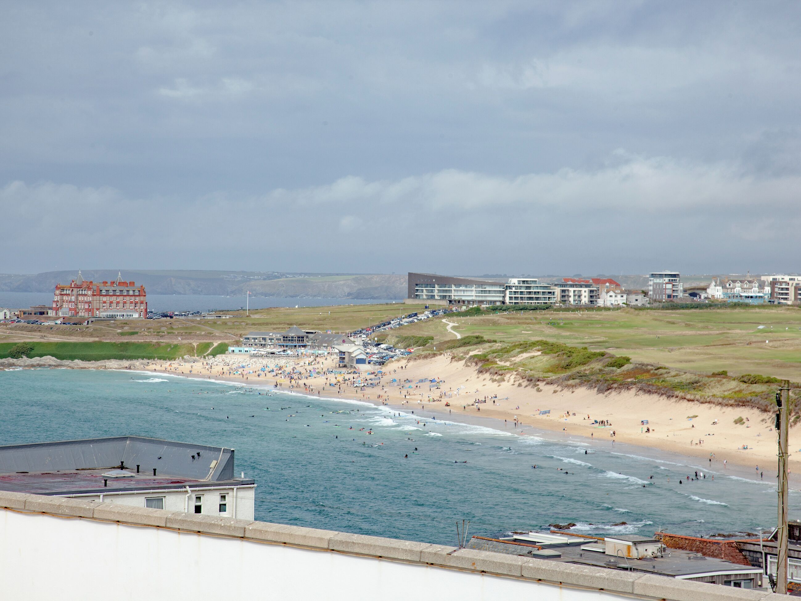 A coastal hotel with a beach view, a parking area, and a large building with multiple floors.