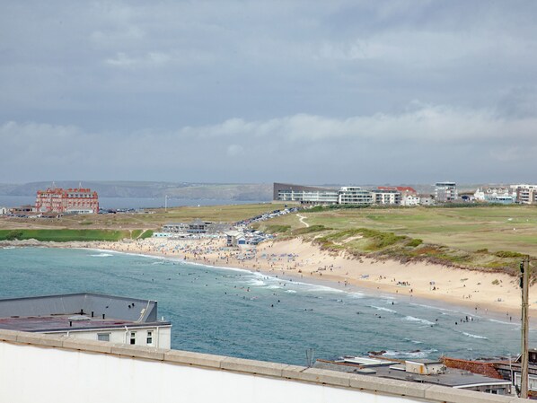 A coastal hotel with a beach view, a parking area, and a large building with multiple floors.