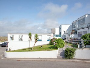 A modern building with large windows, a grassy area with plants, and a clear sky.