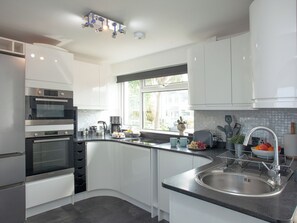 A modern kitchen with built-in appliances, a curved island with a sink, and a window providing natural light.