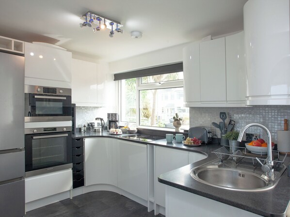 A modern kitchen with built-in appliances, a curved island with a sink, and a window providing natural light.