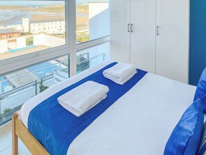 Een slaapkamer met een bed, een raam en uitzicht op gebouwen.