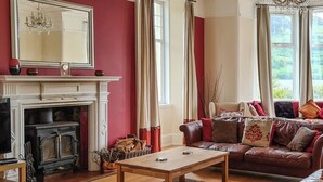 Una sala de estar con chimenea, sofá de cuero y un espejo grande.