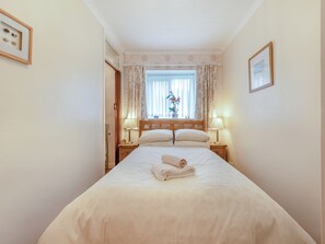 Habitación de hotel con cama, dos mesitas de noche, una ventana con cortinas y un cuadro en la pared.