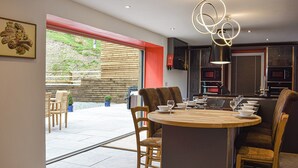 A modern kitchen with a central island, dining area with chairs, and a view of the outdoor patio.