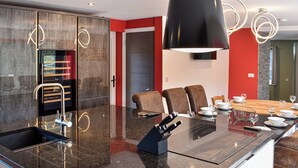 A modern kitchen with a large island, stainless steel appliances, and a dining area with chairs and table set for a meal.