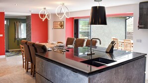 A modern kitchen with a central island, bar stools, and a dining area with chairs.