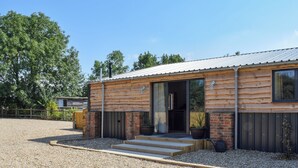 Ein modernes Blockhaus mit Kiesauffahrt, Holzstufen und einem großen Fenster.
