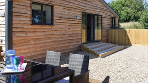 Eine Blockhütte mit einer Terrasse, Sitzgelegenheiten im Freien und einem Holzzaun.