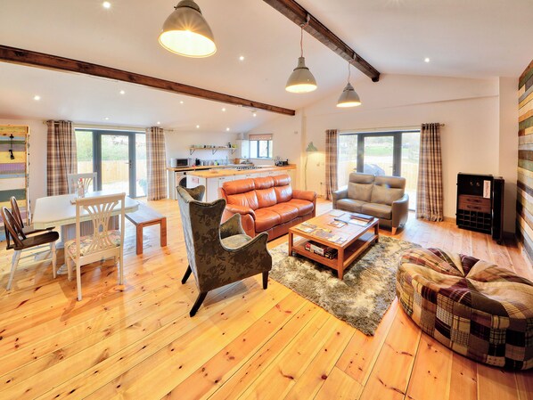 A spacious living room with a wooden floor, leather sofas, a coffee table, and a television.