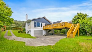 A modern two-story house with a covered patio and a wooden staircase.