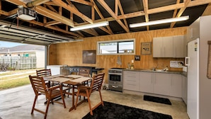 Cocina moderna con vigas de madera, una mesa de comedor con sillas, un refrigerador y una ventana con vista a un patio trasero.