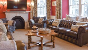 A living room with a fireplace, a television, a sofa, and a coffee table. - Pitcairn House-UK41255 (Keswick)