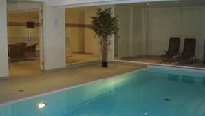 An indoor swimming pool with a clear view of the adjacent lounge area, including seating and a potted plant. - Excl. Apartment close to the beach, swimming pool, sauna, WLAN, free spa card, max. 3 pers. (Zempin)