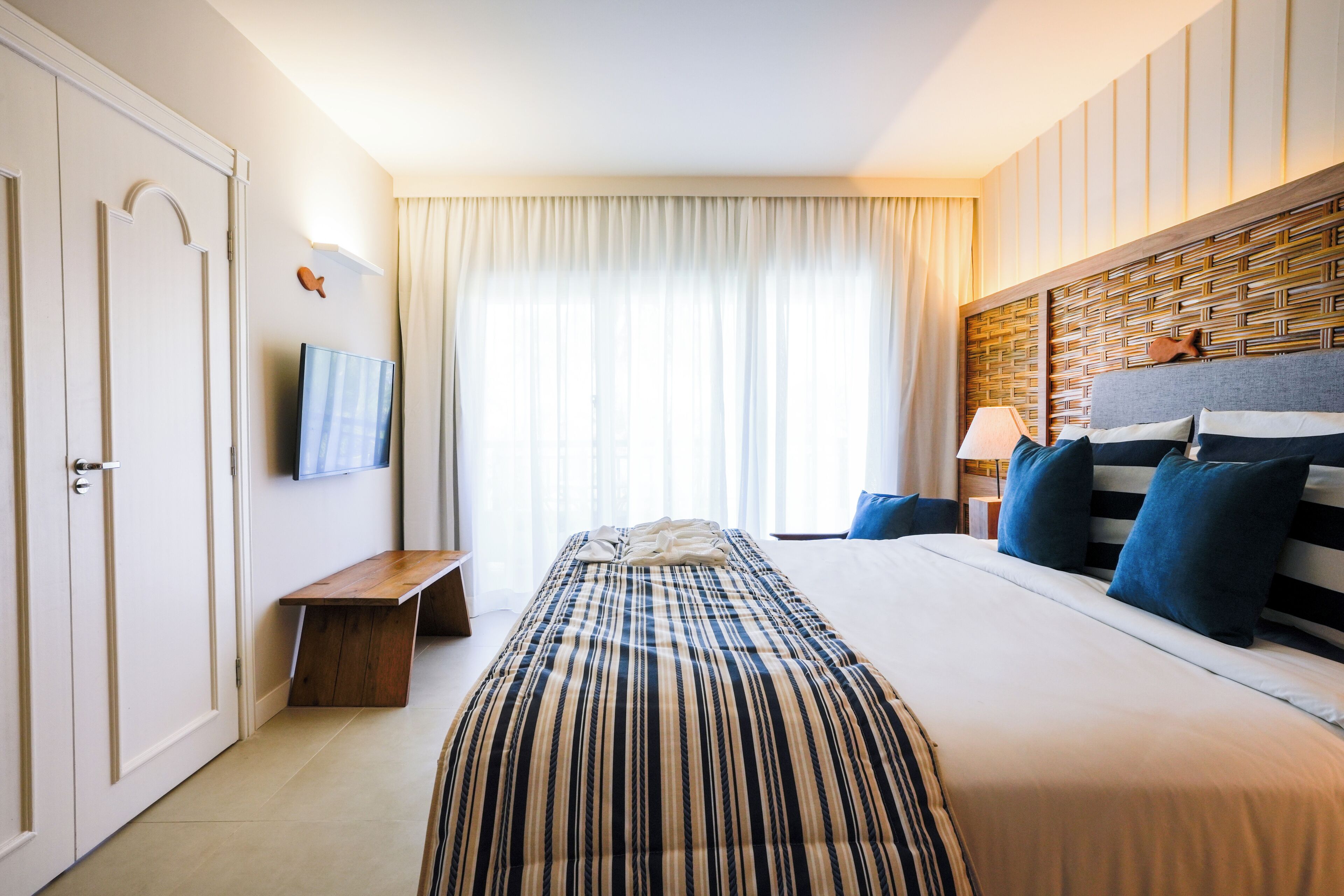 Une chambre d’hôtel avec un lit, une télévision, une table de chevet et une fenêtre avec des rideaux.