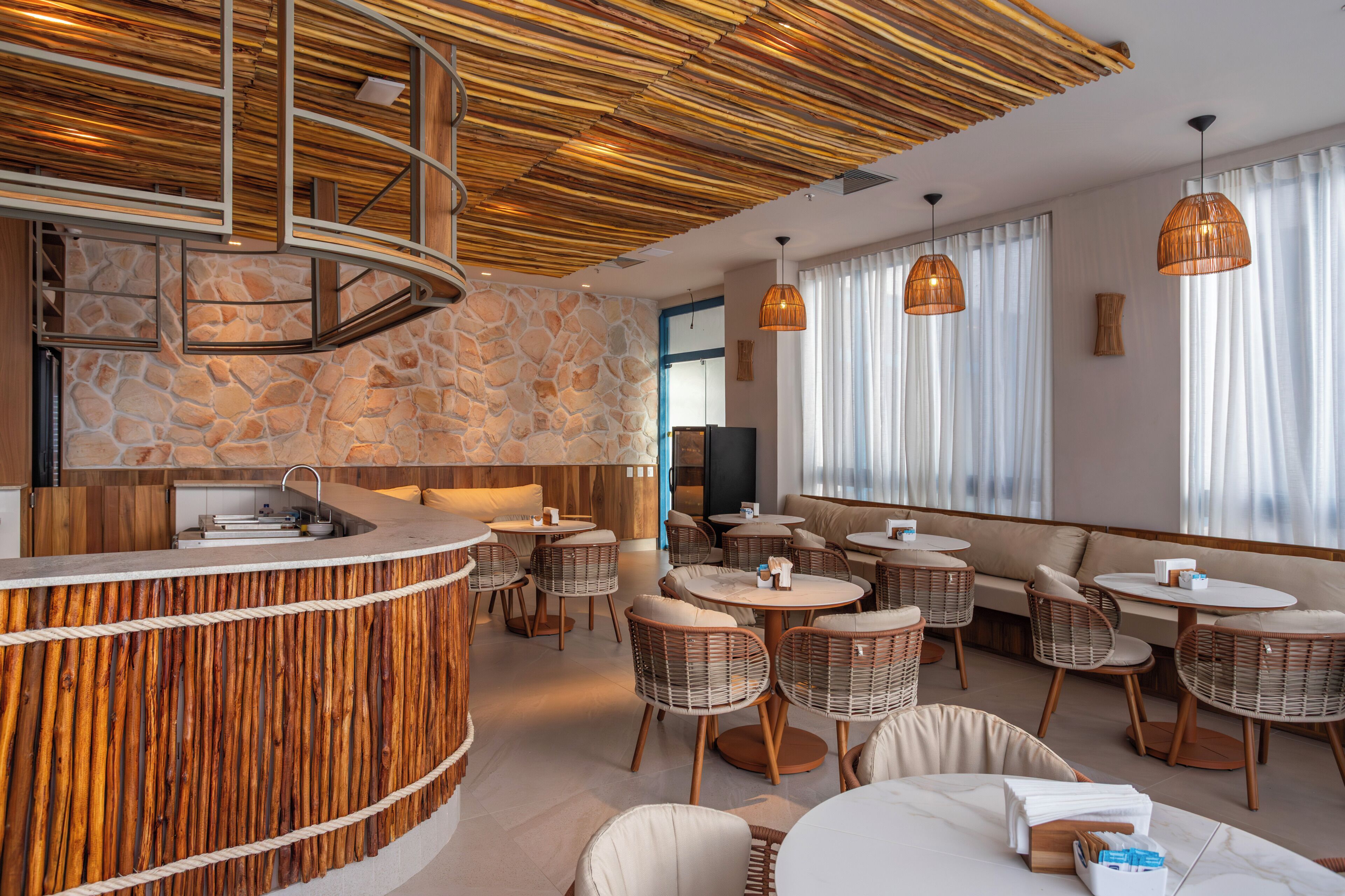 A modern interior with a stone wall, wooden ceiling, and wicker furniture.
