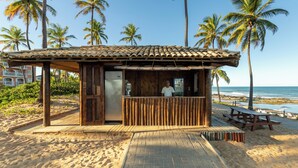 A beachside wooden structure with a tiled roof, a counter, and a bench.