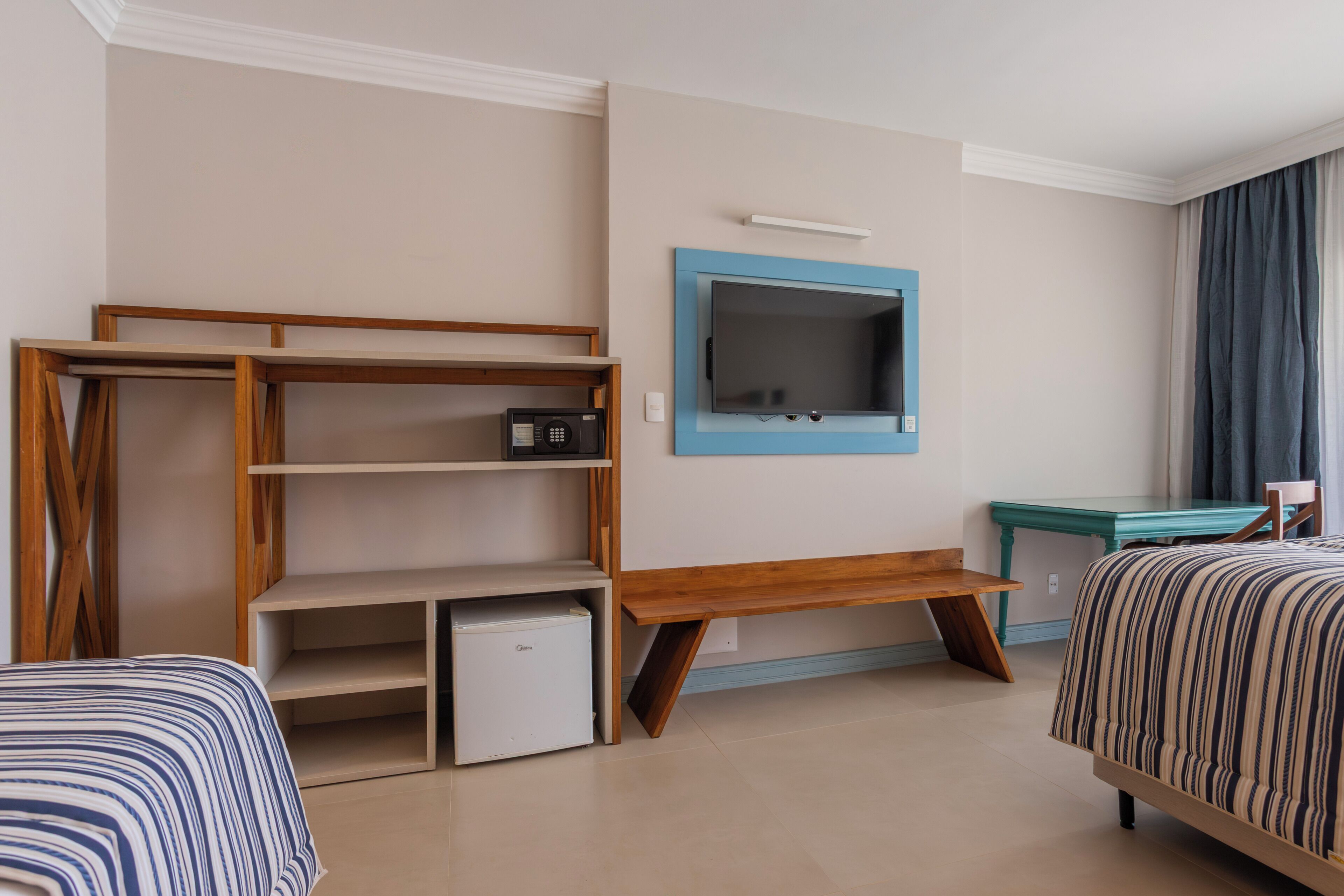 A hotel room with a bed, a desk, a TV, and a small refrigerator.