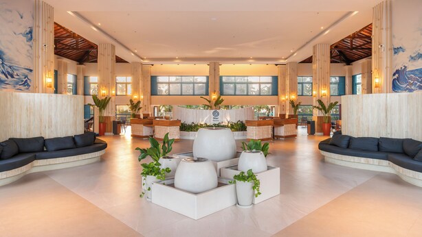 A spacious lobby with a reception desk, seating areas, and large windows.