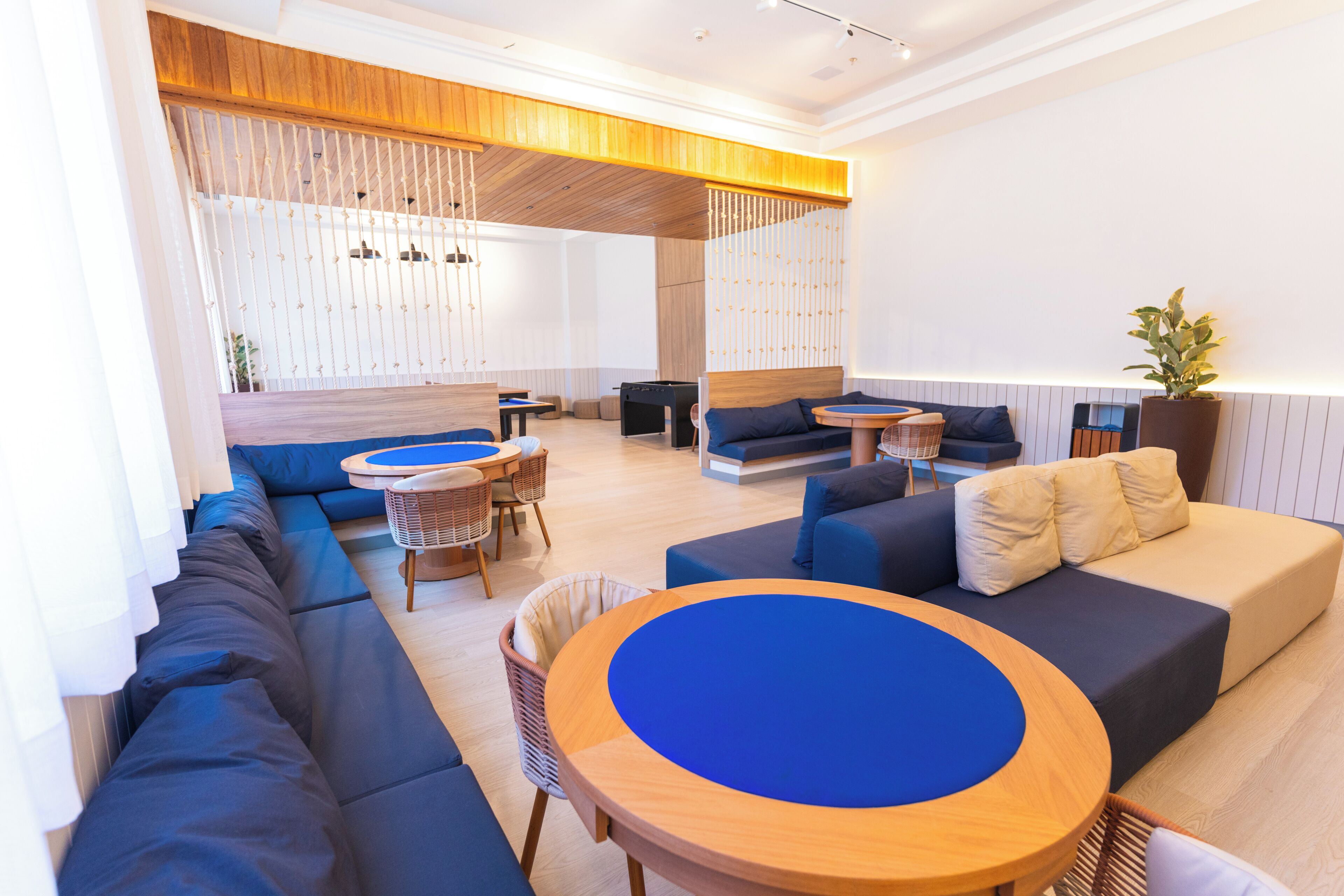 Un espace de détente moderne avec des canapés, une table ronde en bois et un coin salon agrémenté d’une plante.