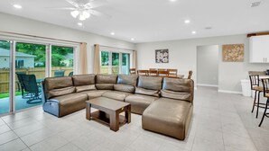 Uma sala de estar espaçosa com sofá seccional, mesa de centro e ventilador de teto.