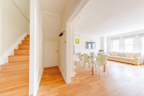 Un vaste espace de vie comprenant un escalier en bois, un coin repas avec des chaises et un canapé.