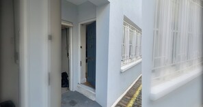 A narrow hallway with a blue door and a window with white blinds. - Spacious and Central 3 Bedroom House in Paddington (London)