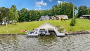 Une propriété au bord du lac, dotée d’un quai, d’un abri pour bateaux et d’une pelouse verdoyante.