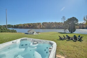 Un bain à remous avec vue sur un lac et une maison en arrière-plan.