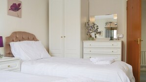 Une chambre à coucher comprenant un lit, une armoire, une commode et un miroir.