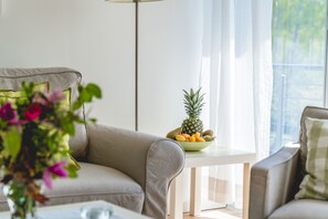 Uma sala de estar moderna com um sofá, uma mesinha com uma tigela de frutas e um abajur.