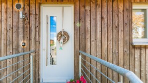 A wooden cabin with a white door, a metal railing, and a wreath hanging on the door. - Lakeview 2 Lake Salem child-friendly bathing lake W LAN (Salem)