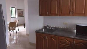 Een keuken met houten kastjes, een roestvrijstalen spoelbak en een zwarte magnetron.