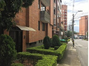 A multi-story residential building with a brick facade, a gated entrance, and a well-maintained hedge. - Apartment in Laureles (the most Coll neighborhood in the world) spacious and well located.  (Medellín)