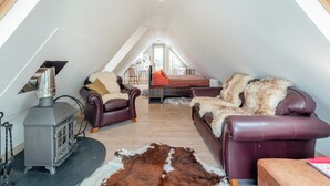 Acogedor dormitorio en el ático con chimenea, sofás de cuero y alfombra de piel.