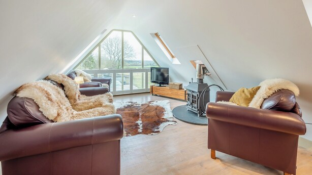 Un espacioso dormitorio tipo loft con un amplio tragaluz, una chimenea acogedora y una zona de estar cómoda.