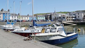 Un puerto con barcos amarrados, un muro de piedra y edificios al fondo.