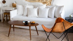 Een moderne woonkamer met een witte bank, een houten salontafel, een fauteuil van bruin leer en een stenen muur.